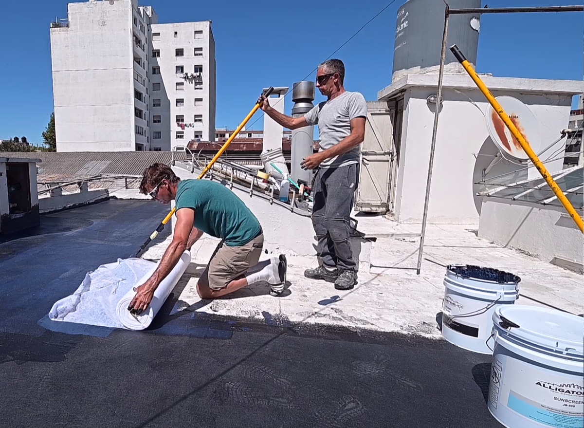 Equipo de trabajo aplicando impermeabilización en terraza